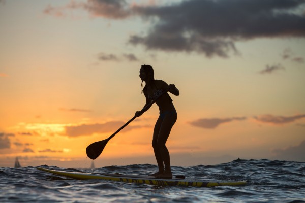 Young woman on Standup Paddle Board, SUP, off shore at Waikiki Beach, on Oahu, Hawaii?s southern shoreline.
